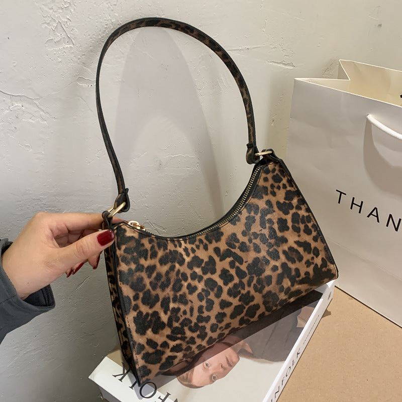 Leopard print handbag held by a hand with a white background