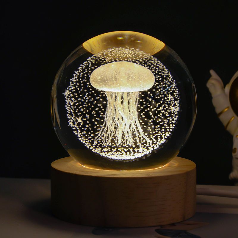 Glass sphere with a jellyfish inside on a wooden base against a dark background