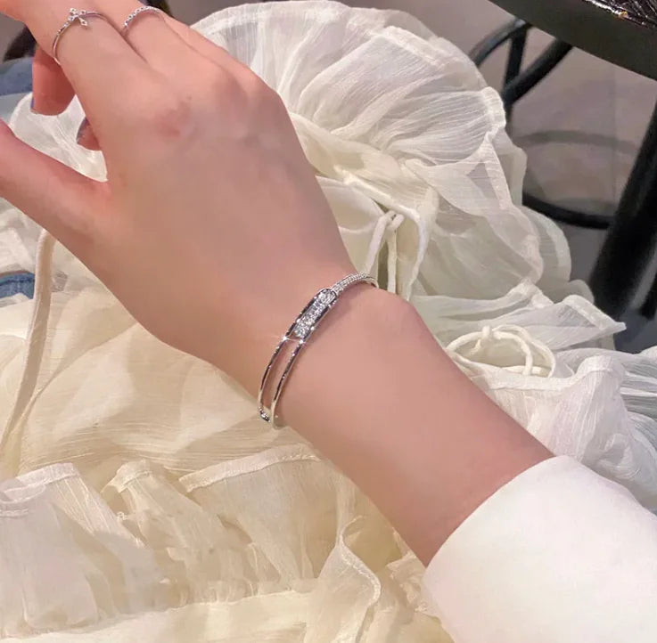 Hand wearing a silver bracelet with white fabric background
