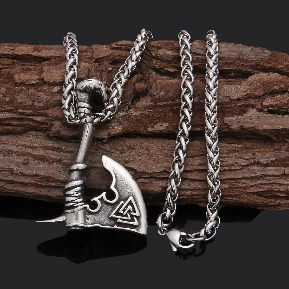 Silver axe-shaped pendant with chain on a wooden background