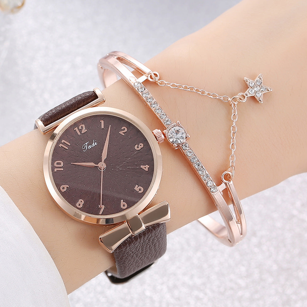 Wrist wearing a brown watch with rose gold accents and two bracelets on a light background