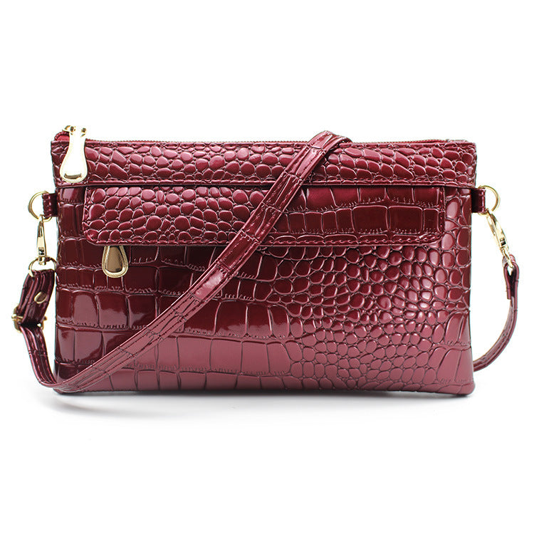 Maroon crocodile-textured handbag with gold accents on a white background