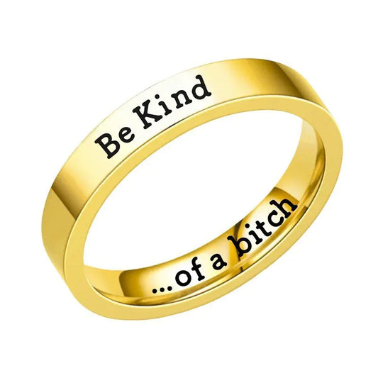 Gold ring with 'Be Kind' on one side and '...of a bitch' on the other, on a white background