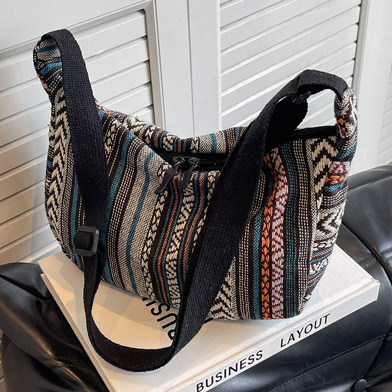 Patterned handbag with a black strap on a white surface