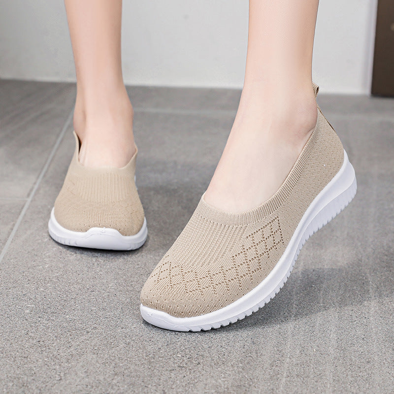 Beige slip-on shoes with white soles on a gray floor.