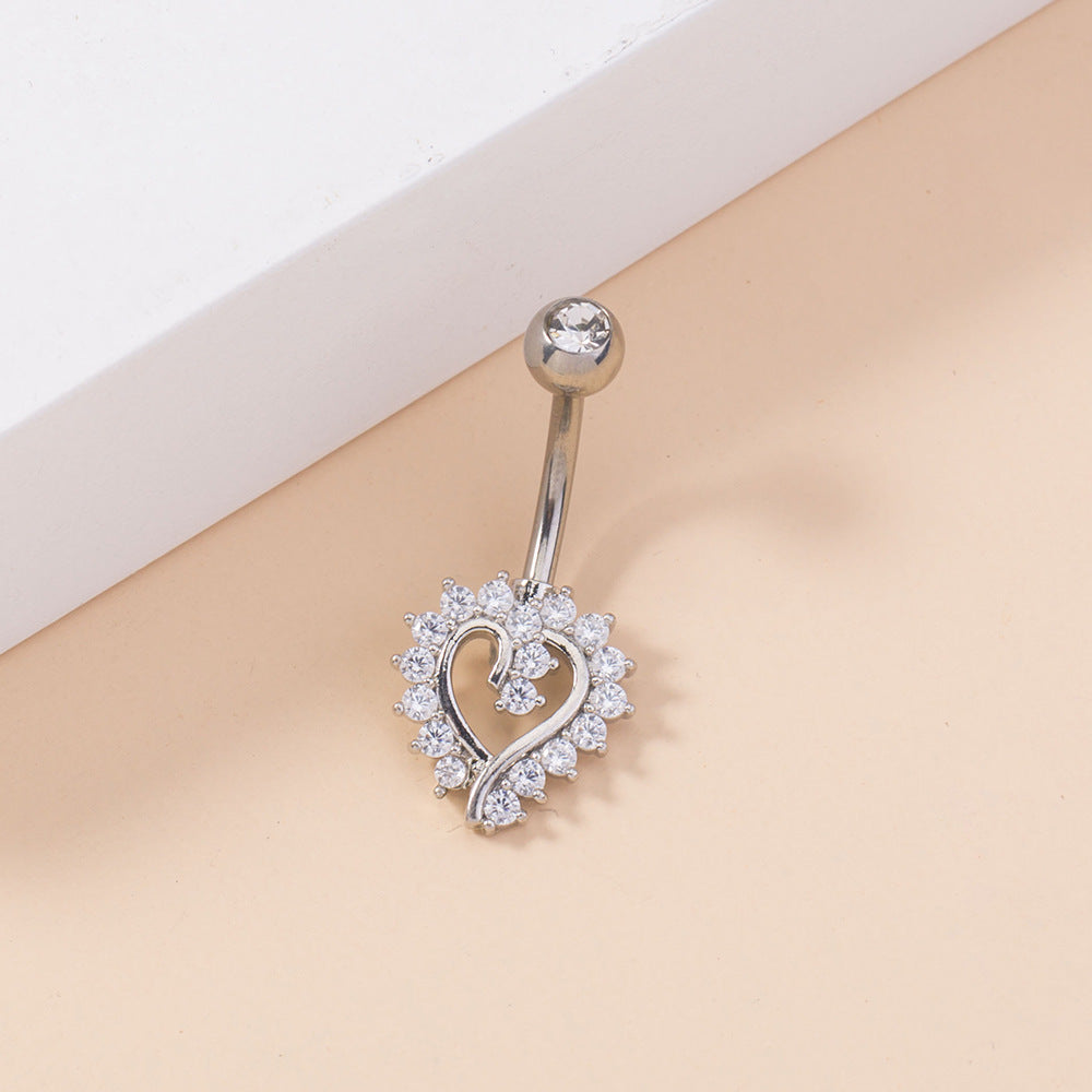 Silver belly button ring with heart design on a beige background