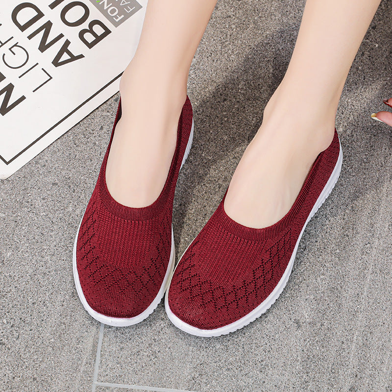 Red slip-on shoes worn by a person on a gray pavement.