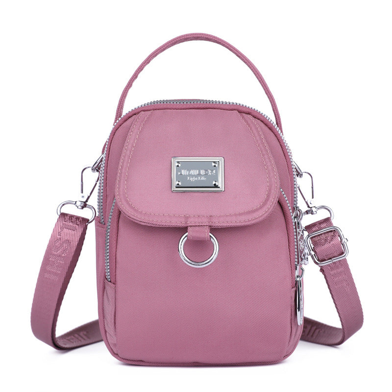 Pink crossbody bag with silver accents on a white background