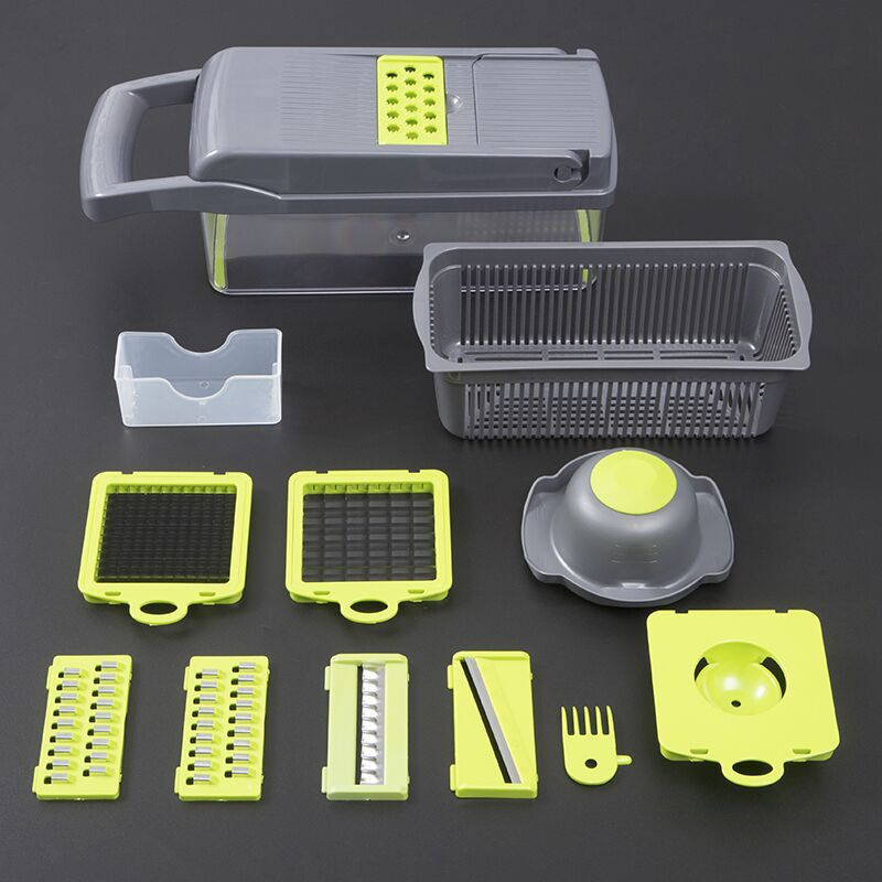 Set of kitchen tools including a gray mandoline slicer and various attachments on a dark background