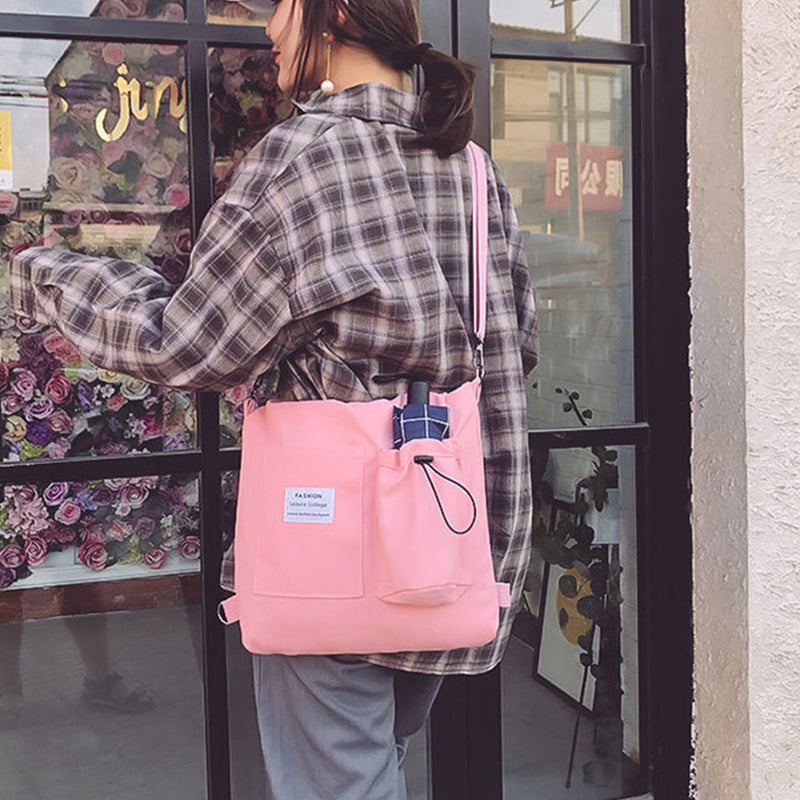 Person wearing a pink backpack with a plaid shirt in front of a store window.