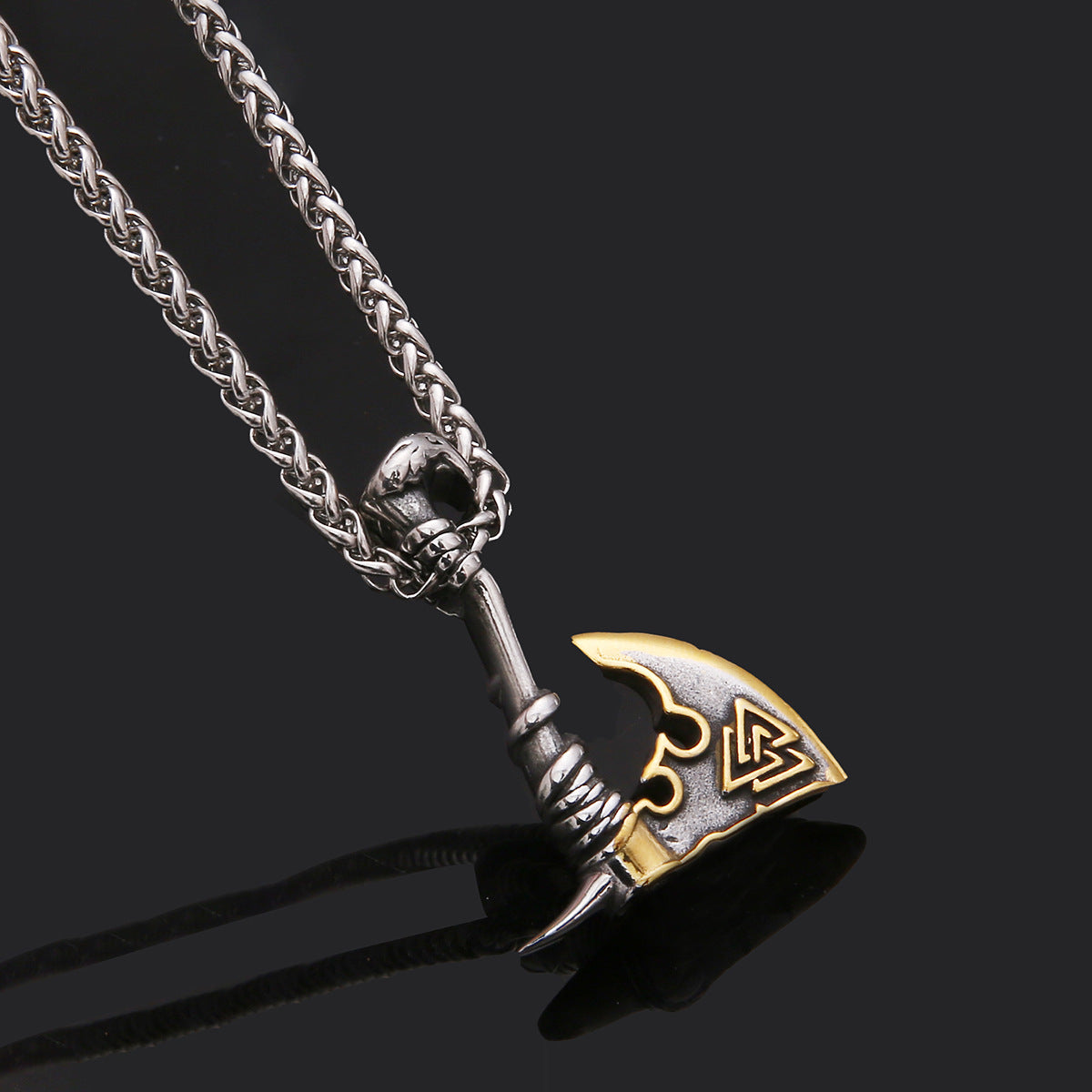 Metallic axe-shaped pendant on a chain against a black background