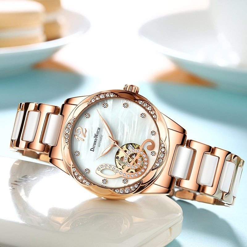 Rose gold watch with a white face on a reflective surface