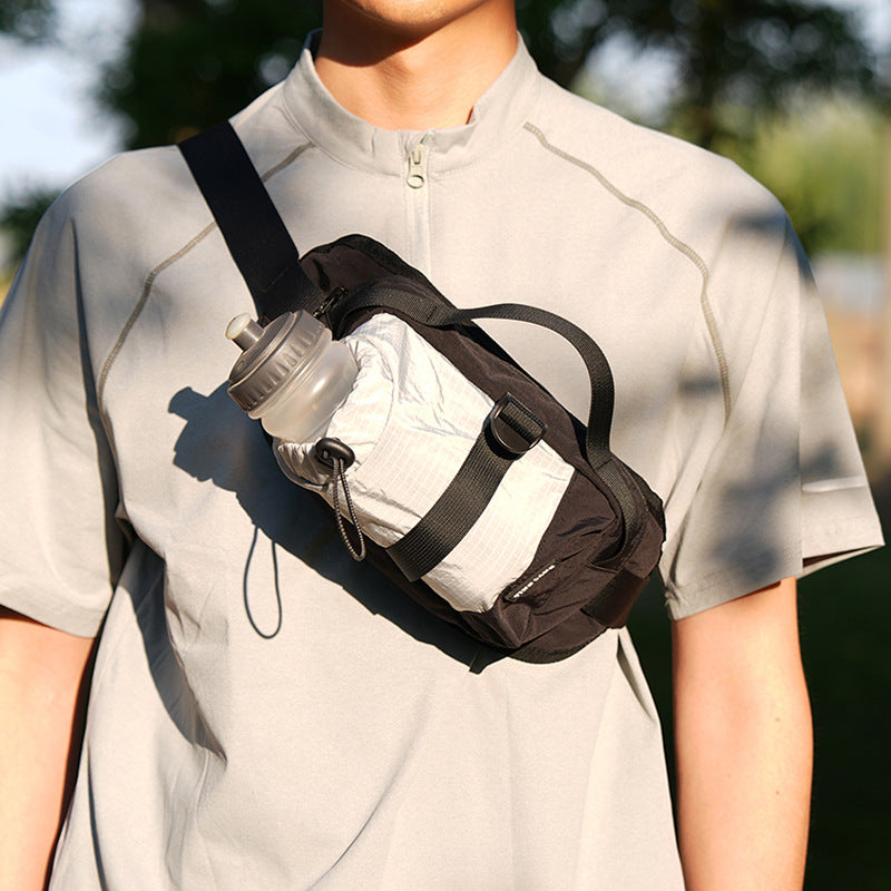 Person wearing a black sling bag with a water bottle on a blurred outdoor background