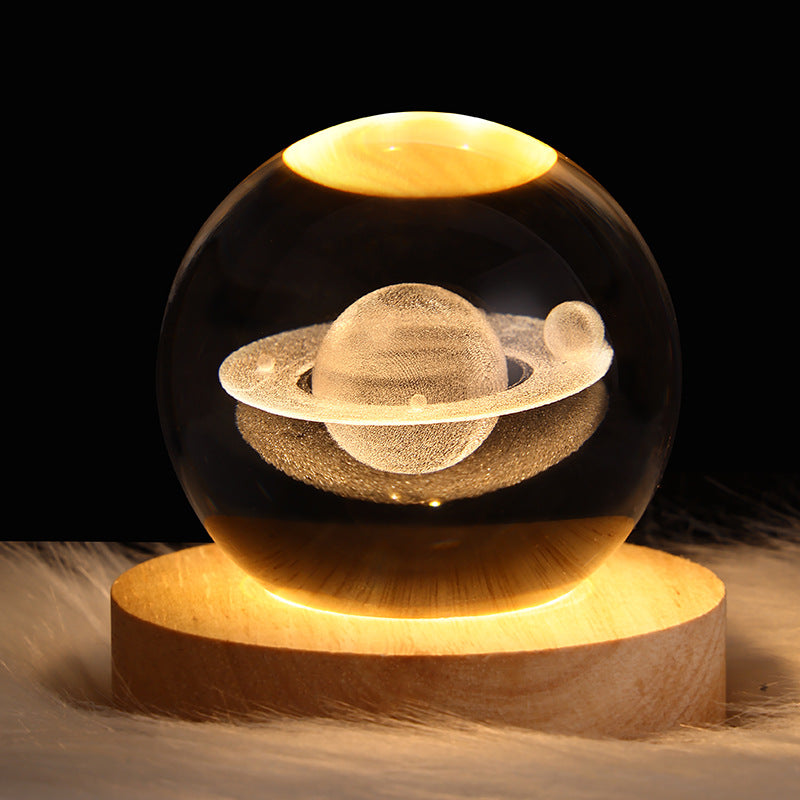 Glass sphere with a celestial design on a wooden base against a dark background