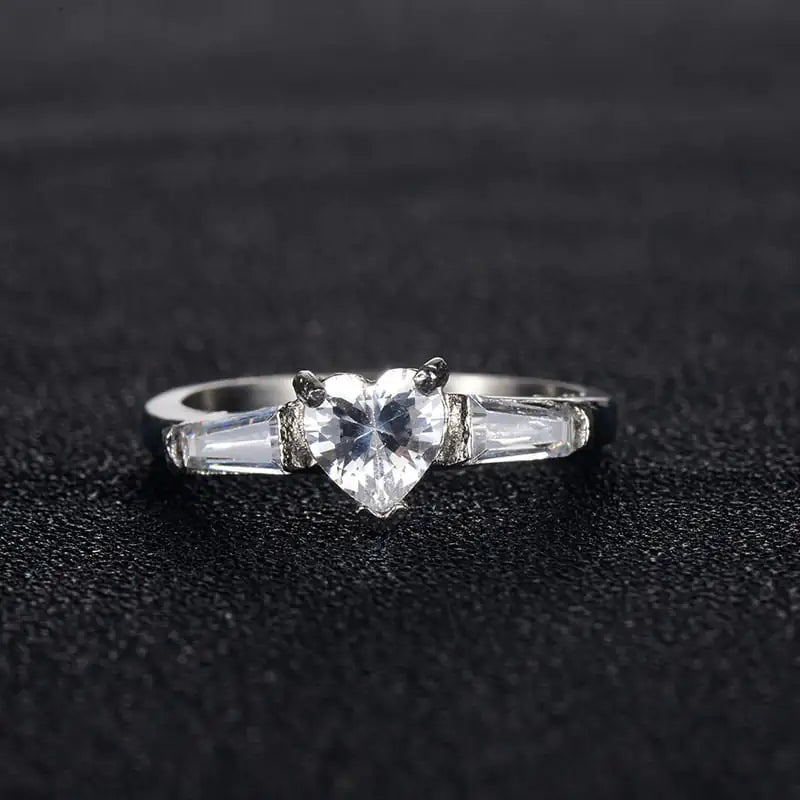 Silver ring with a clear gemstone on a black textured background