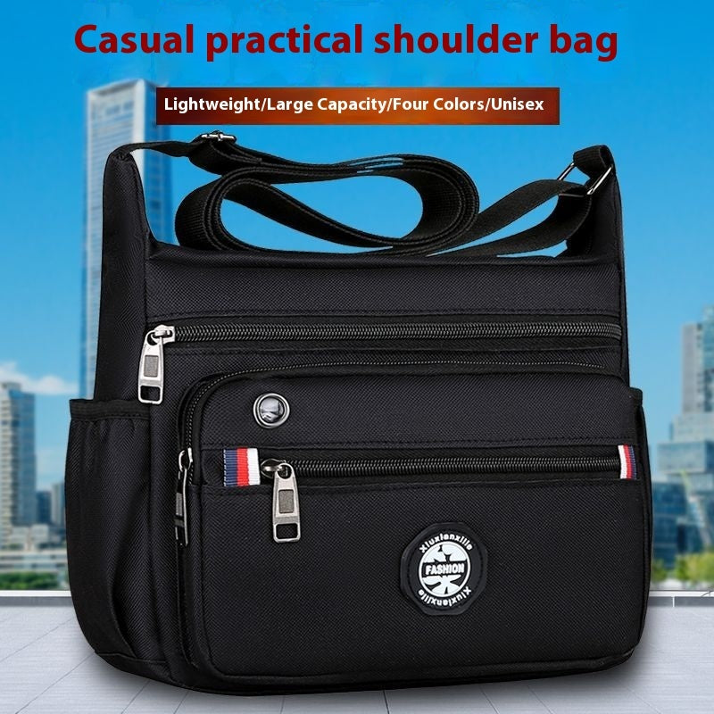 Black shoulder bag with multiple pockets and zippers on a cityscape background