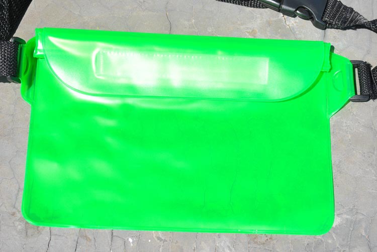 Green waterproof bag with a strap on a concrete surface