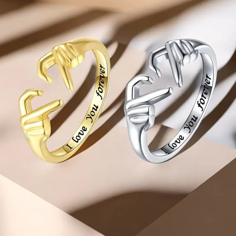 Gold and silver rings with 'I love you forever' engraving on a beige background