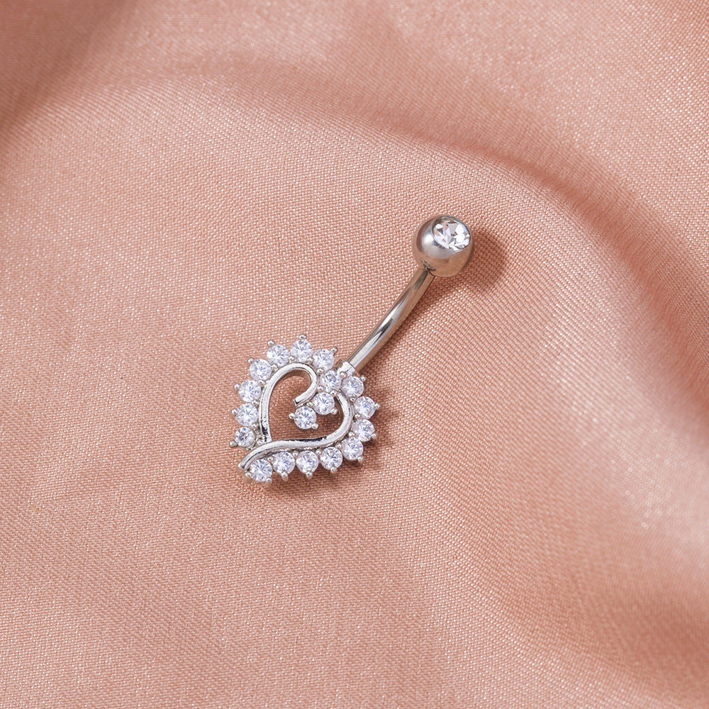 Silver belly button ring with heart design on a pink fabric background