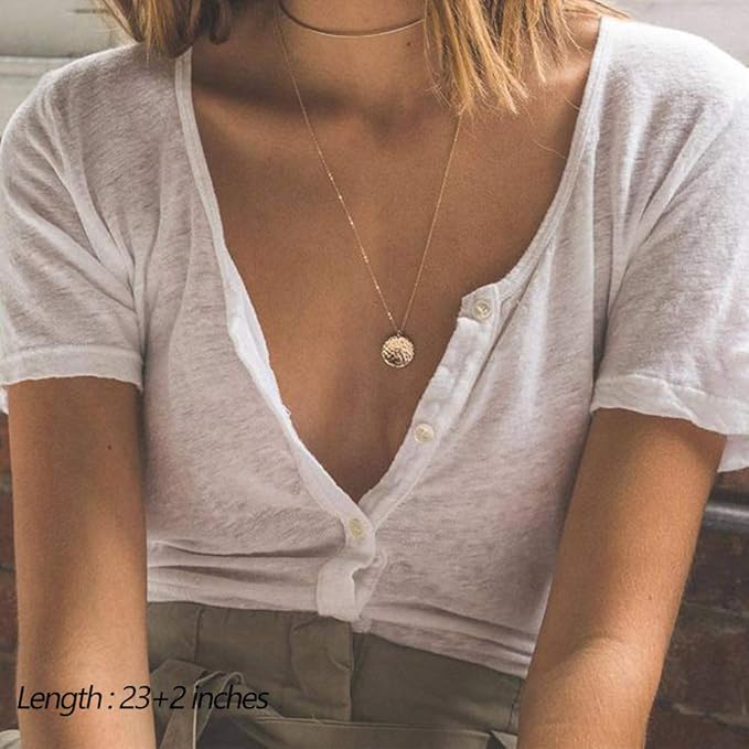 Person wearing a white shirt with a necklace featuring a tree pendant.