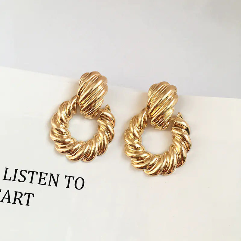 Gold hoop earrings on a white surface with text 'LISTEN TO ART' in the corner.