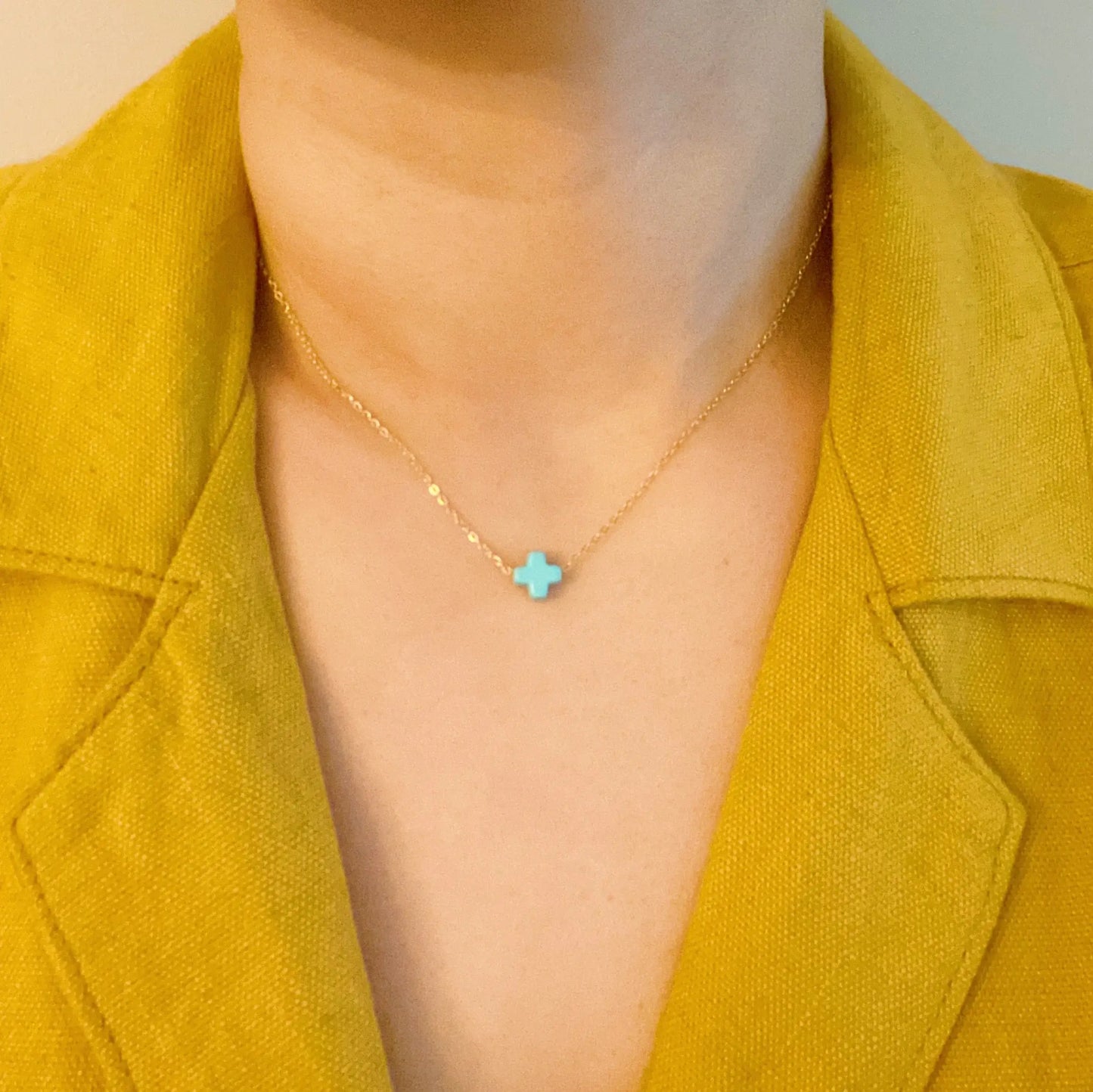 Necklace with a blue star pendant worn by a person in a yellow jacket.
