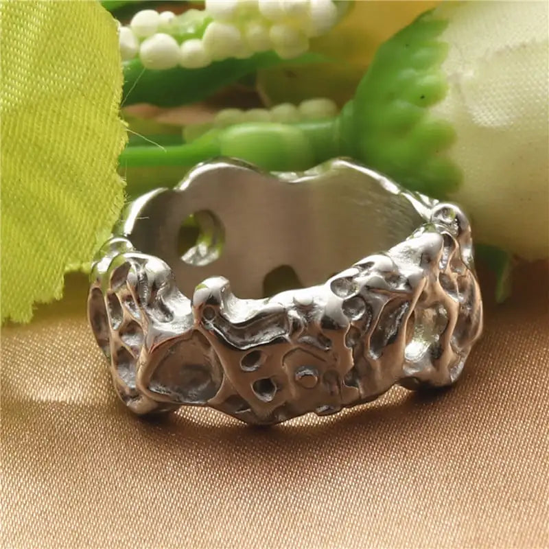 Silver ring with textured design on a beige fabric background