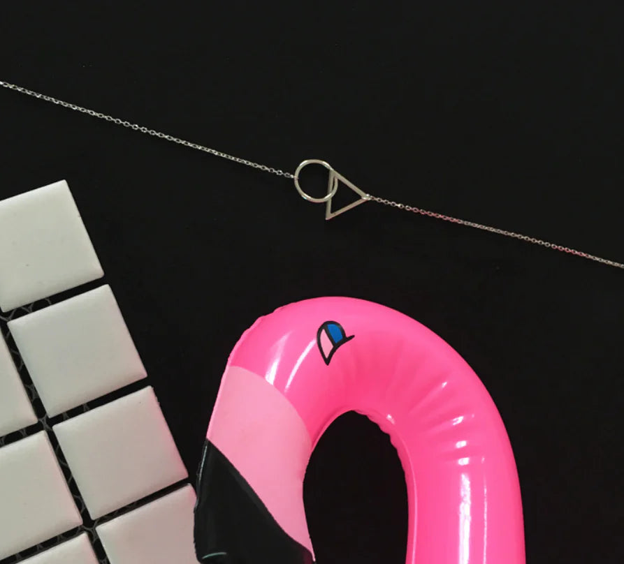 Pink inflatable flamingo pool toy with a necklace on a black background