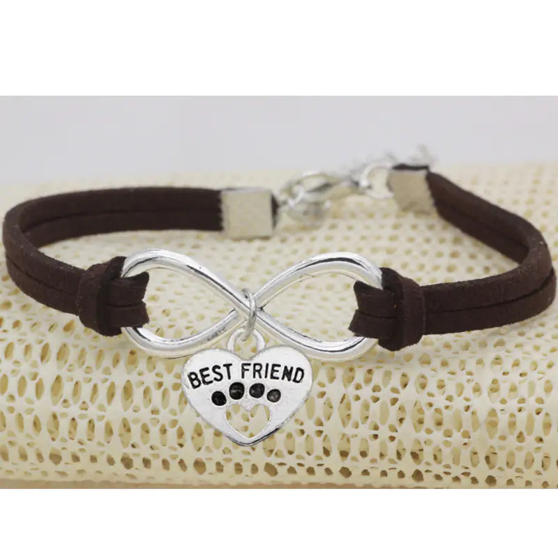 Bracelet with infinity symbol and 'Best Friend' heart charm on a textured surface