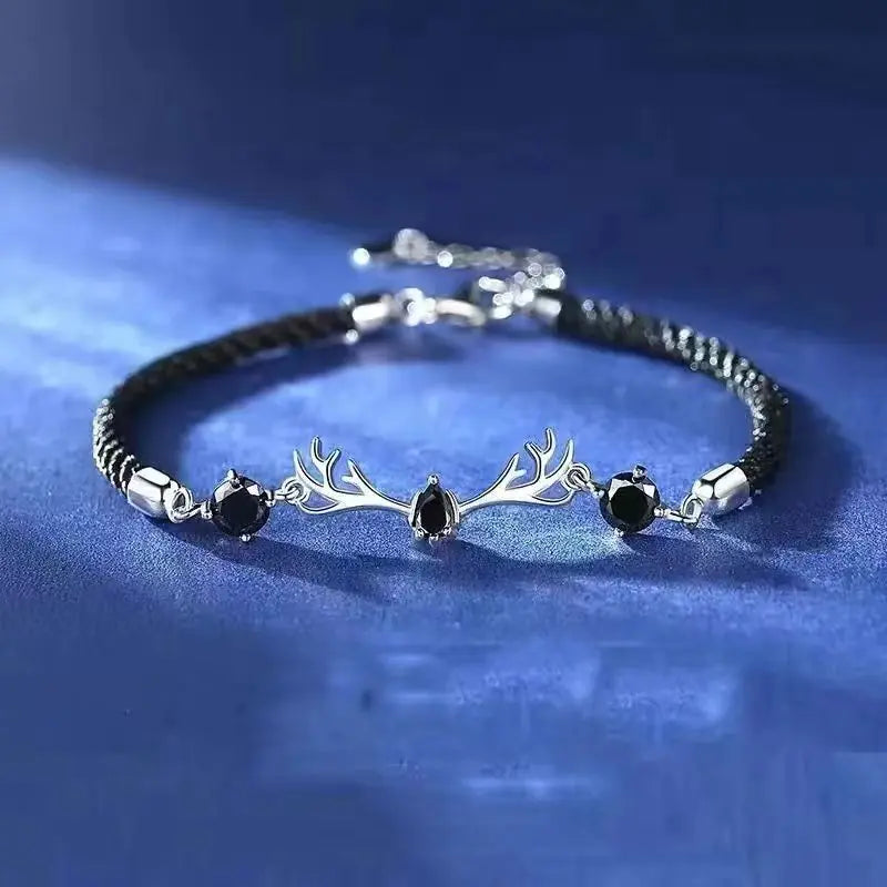 Bracelet with silver antler design and black stones on a blue background