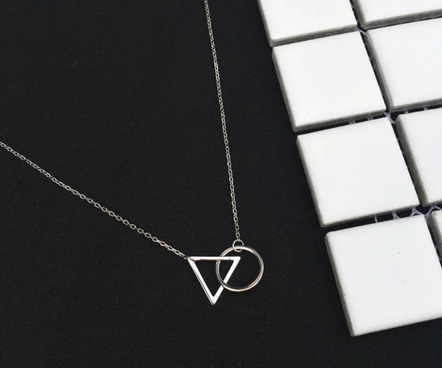 Silver necklace with geometric pendants on a black surface