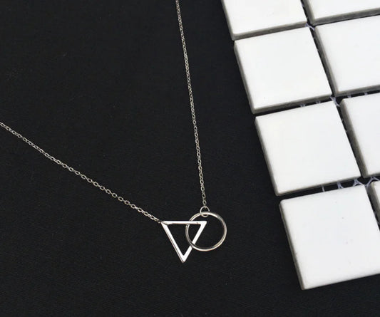 Silver necklace with geometric pendants on a black surface