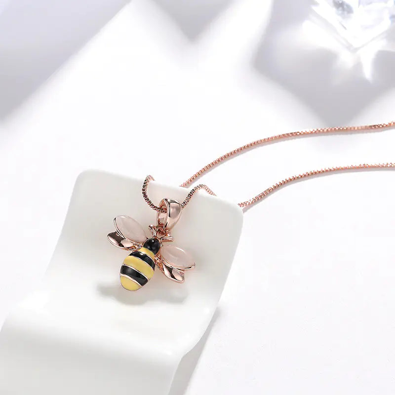 Rose gold bee pendant necklace on a white background
