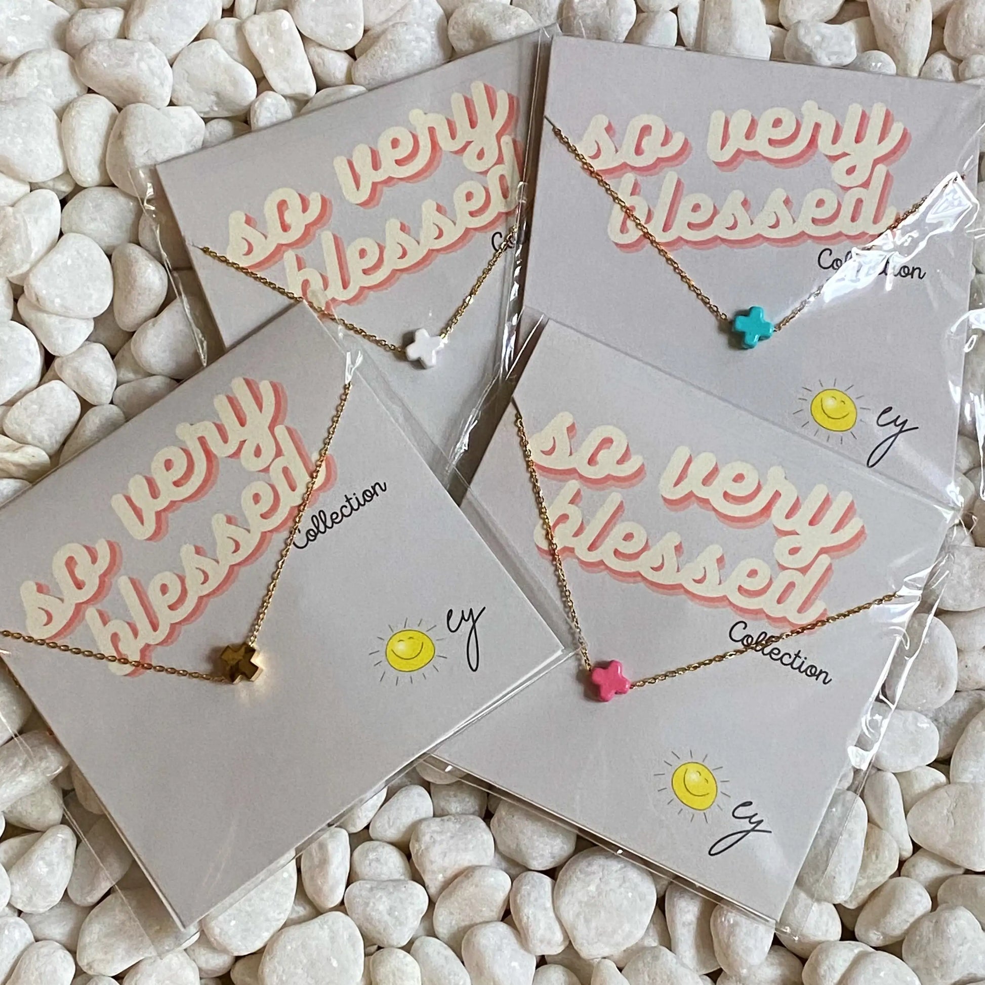 Necklaces on cards with 'so very blessed' text on a pebble background