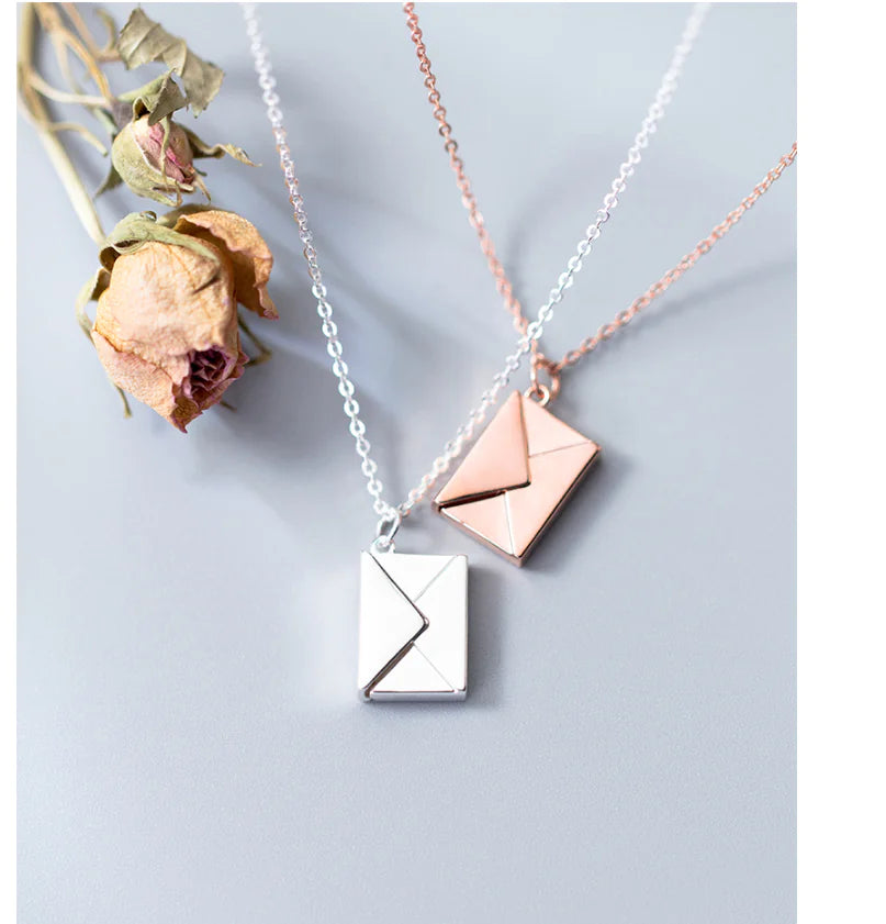 Two necklaces with envelope pendants on a light gray background