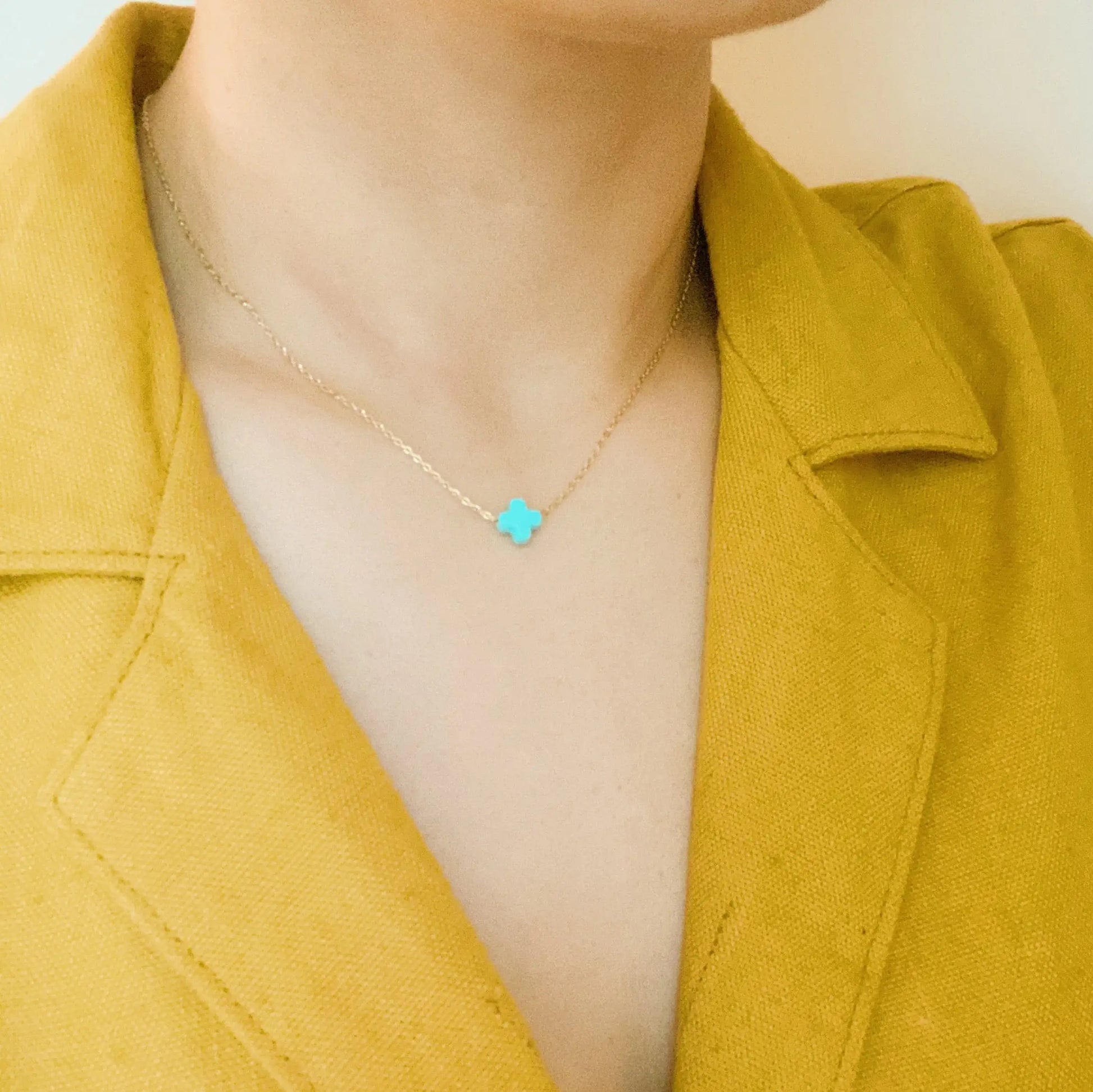 Necklace with a turquoise pendant worn by a person in a yellow jacket.