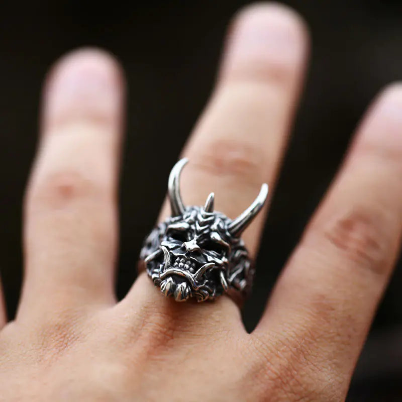 Silver dragon ring on a person's finger with a dark background