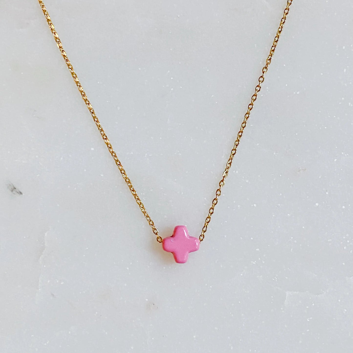 Gold necklace with a pink star pendant on a light gray background