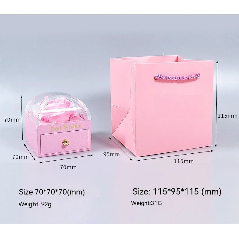 Pink jewelry box with clear lid and pink gift bag with dimensions and weight on a light gray background