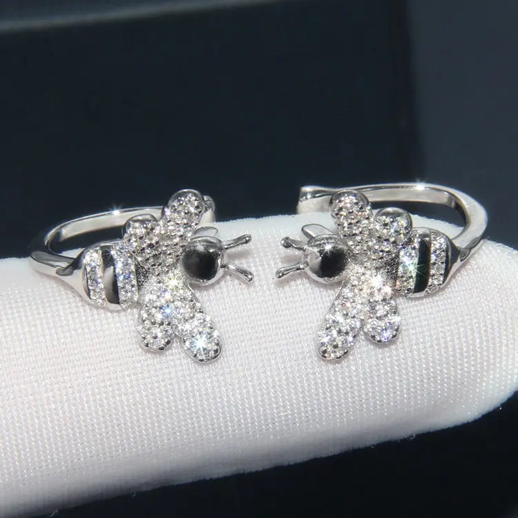 Silver teddy bear-shaped earrings on a white stand with a dark background