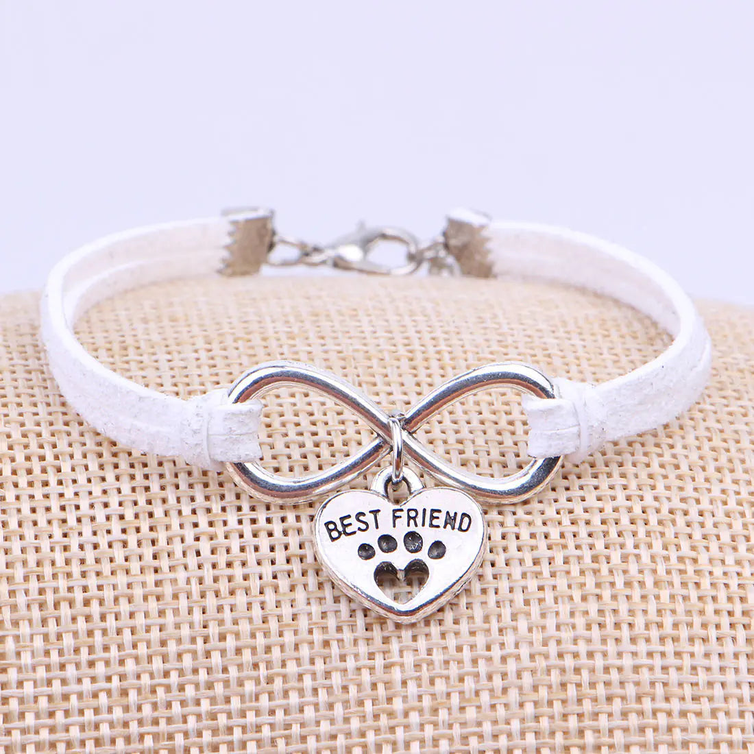Bracelet with infinity symbol and 'Best Friend' heart charm on a textured surface