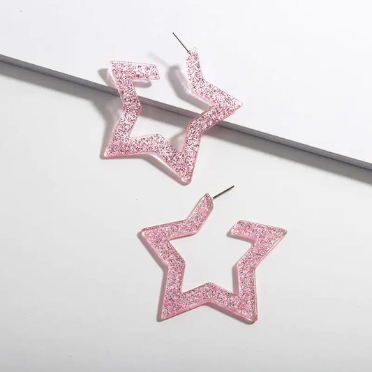 Pink glittery star-shaped earrings on a light gray background