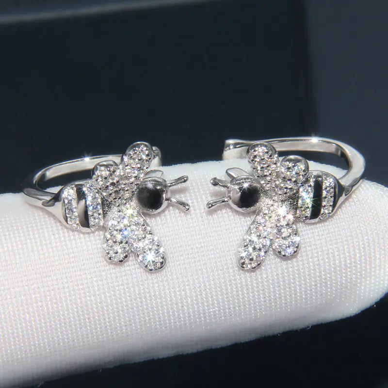 Silver teddy bear-shaped earrings on a white stand with a dark background