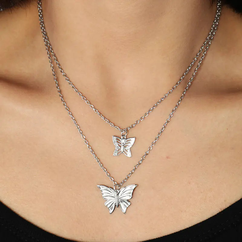 Two silver butterfly necklaces on a person's neck
