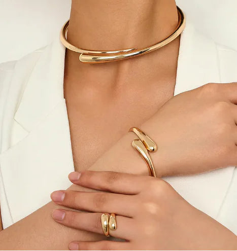 Gold bracelets and rings on a person's wrist and hand against a white background