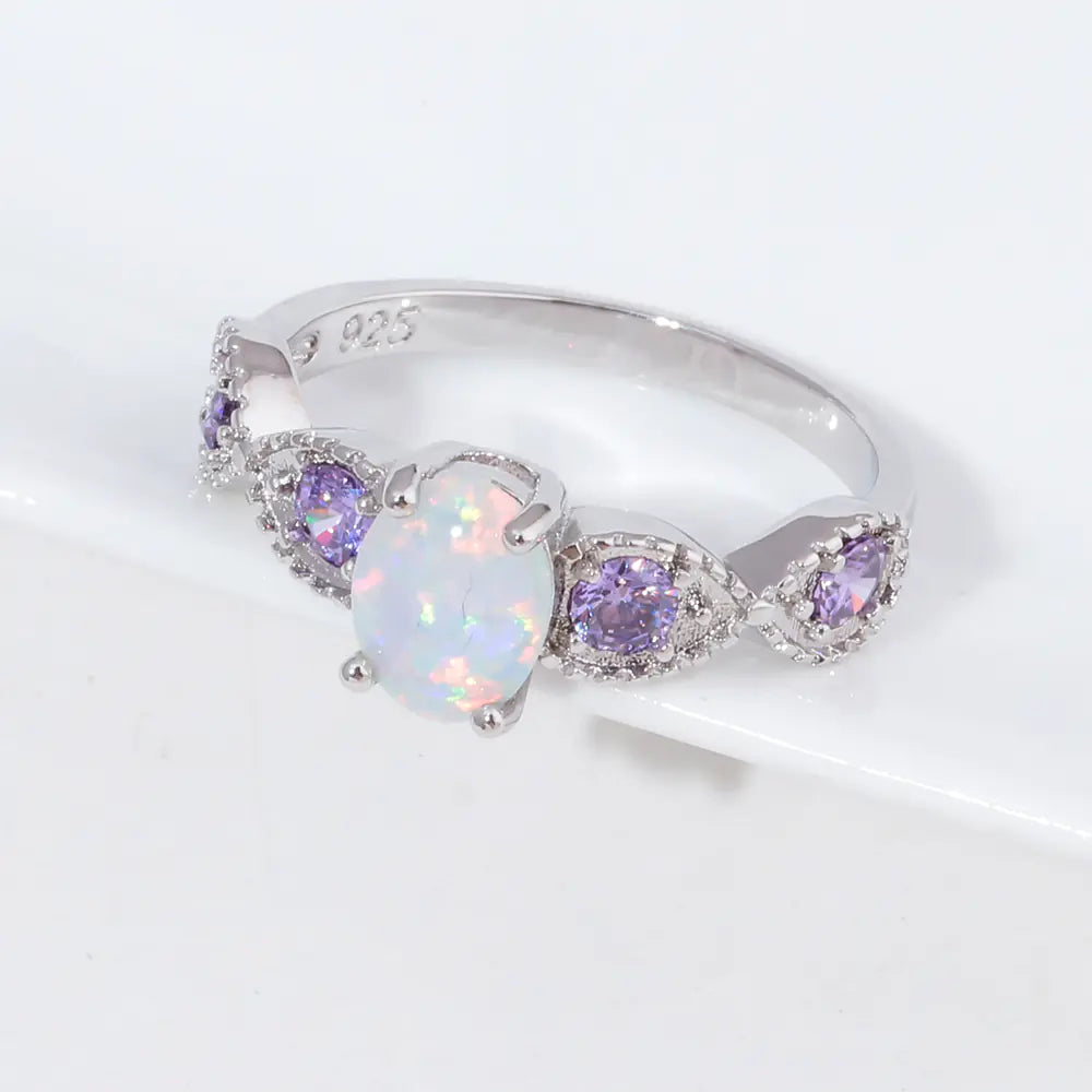 Silver ring with heart-shaped opal and purple gemstones on a white background