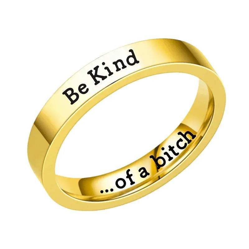 Gold ring with 'Be Kind' on one side and '...of a bitch' on the other, on a white background