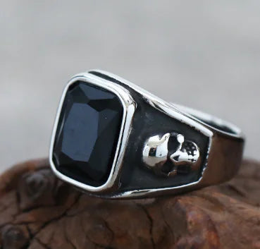 Silver ring with a black stone on a wooden surface