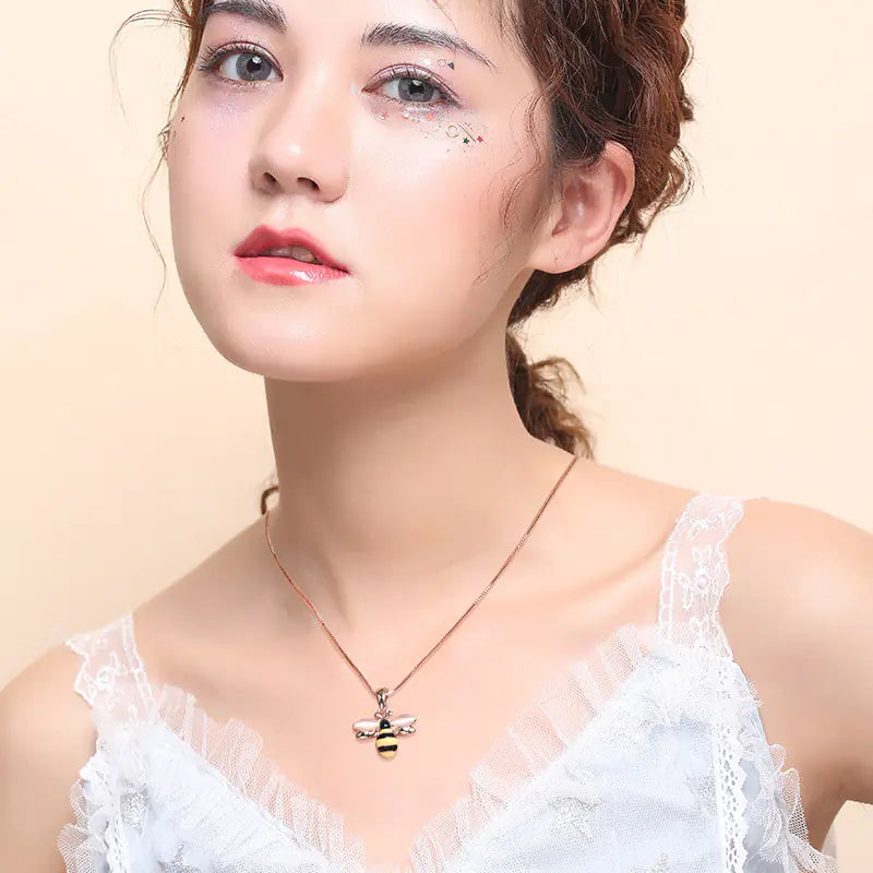 Woman wearing a necklace with a bee pendant against a beige background