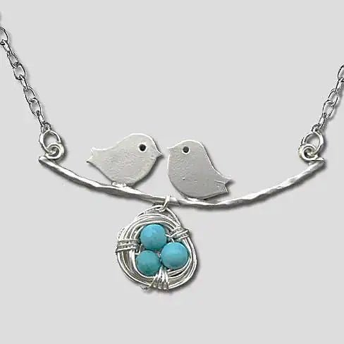 Silver necklace with bird and nest pendant on a light gray background